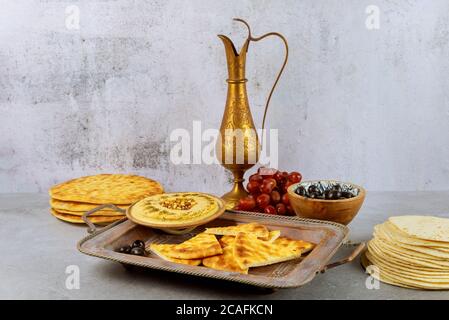 Tavolo da festa indiano con hummus, pane, olive e brocca di rame. Foto Stock