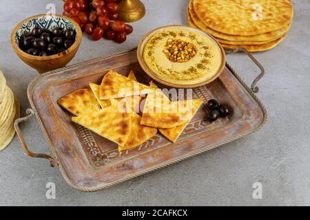 Tavolo da pranzo ebraico con pane pita, hummus e olive su sfondo ligneo. Foto Stock