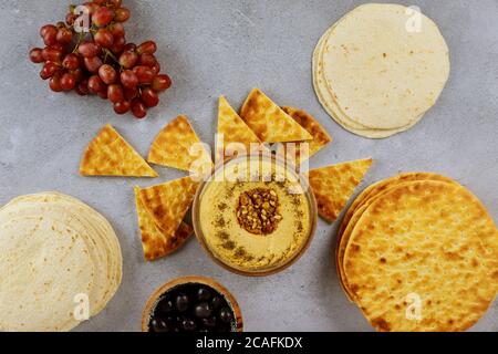 Tavolo da pranzo libanese con pane pita, hummus e olive su sfondo ligneo. Foto Stock