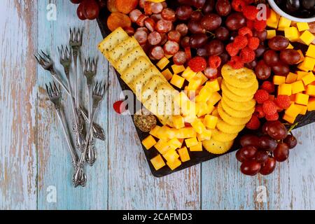 Bordo di salumi con cubetti di formaggio, prosciutto, uva, cracker e albicocche secche. Foto Stock