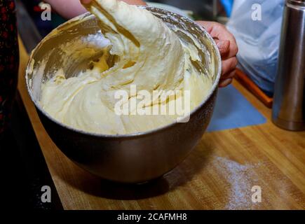 Donna che mescola uova, zucchero e farina nel recipiente del miscelatore. Preparazione dell'impasto per pan di Spagna. Foto Stock