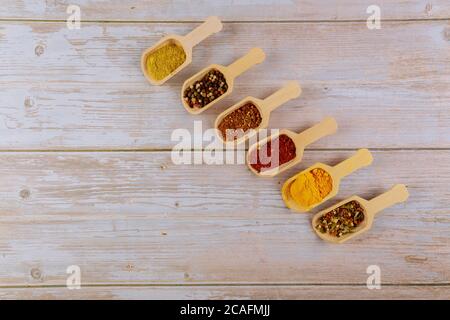 Sei cucchiai di legno di spezie asiatiche su tavolo di legno bianco. Foto Stock