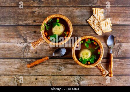 Zuppa di matzo fatta in casa in due pentole con cucchiai su sfondo di legno. Foto Stock