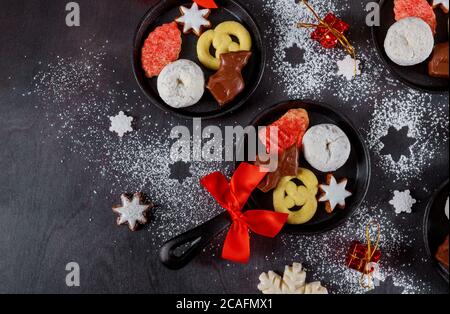 Biscotti di Natale in teglia di ferro con arco rosso su un tavolo di legno scuro. Foto Stock