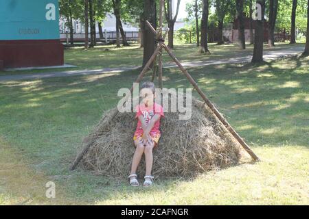 bella ragazza sorridente imparare sotto forma di un gioco in il parco della città nella soleggiata giornata estiva Foto Stock
