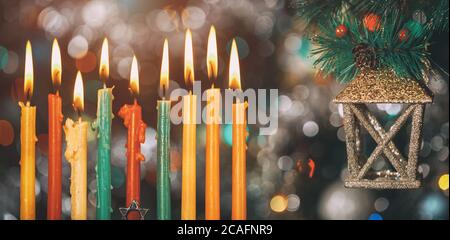 Nove candele colorate brucianti su sfondo colorato con qualche decorazione. Foto Stock