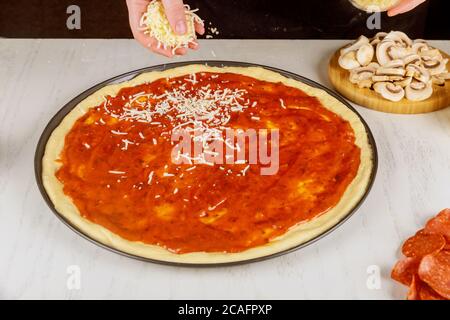 Pizza da donna spruzzata con mozzarella grattugiata. Foto Stock