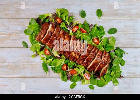 Filetto di maiale al barbecue o filetto su foglie verdi con pomodoro. Foto Stock