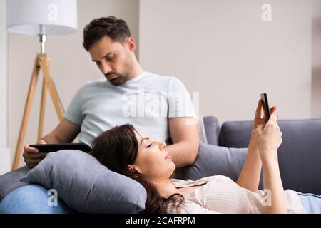 Coppia di famiglia che usa il tablet e il telefono sul lettino Foto Stock