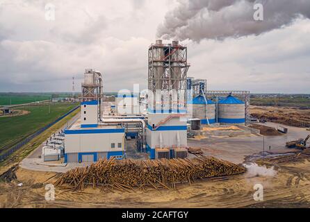 Impianto di lavorazione del legno. Inquinamento dell'aria dalla segheria. Fumo nell'atmosfera. Sega per legno di pino con macchine per la lavorazione del legno. Vista dall'alto, aerea Foto Stock