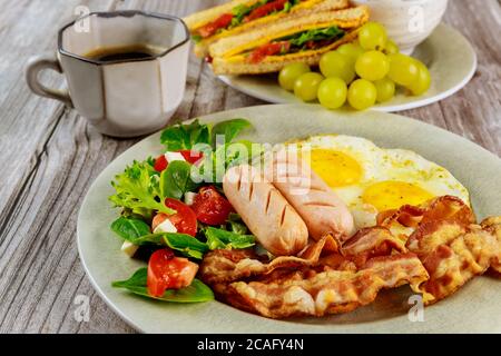 Colazione con uova, salsicce, pancetta, toast e tazza di caffè. Foto Stock