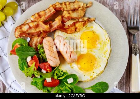 franche di pollo, uova fritte, pancetta e insalata per colazione. Foto Stock