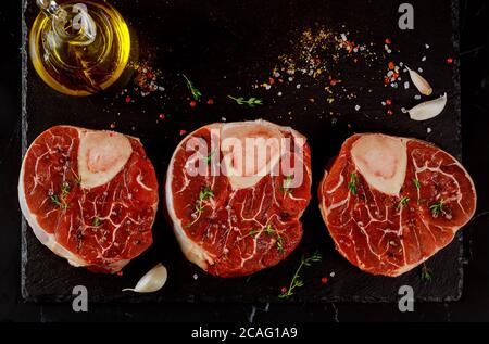 Tre pezzi di manzo fresco crudo con osso con spezie e erbe. Foto Stock