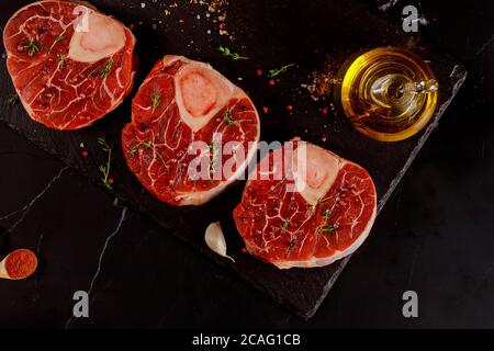 Tre pezzi di manzo fresco crudo con le spezie e l'olio d'oliva. Vista dall'alto. Foto Stock