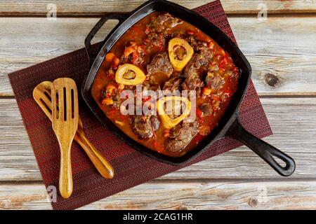 Stinco di manzo cotto con verdure e vino in ghisa. Ossobuco cucina italiana. Foto Stock