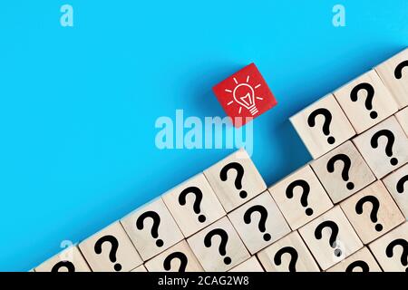 Idea creativa, soluzione o concetto di risoluzione dei problemi. Icone di punti interrogabili e lampadine su cubi di legno su sfondo blu. Foto Stock