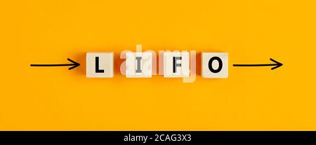 L'abbreviazione commerciale lifo (last in first out) scritta su blocchi di legno con frecce direzionali su sfondo giallo. Foto Stock