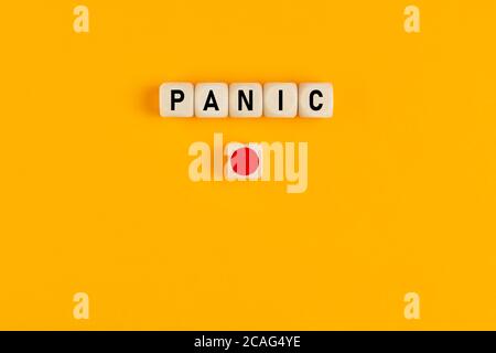 La parola panico scritta su cubi di legno con un pulsante rosso. Concetto del pulsante di emergenza. Foto Stock
