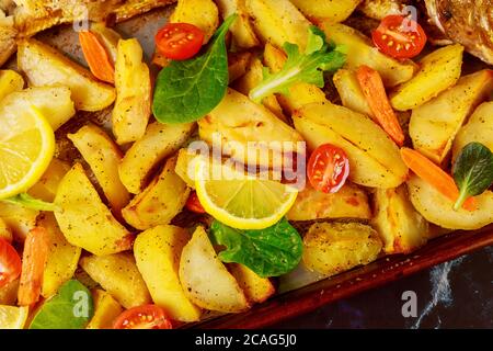 Spicchi di patate al forno con pomodoro fresco e limone. Primo piano. Foto Stock