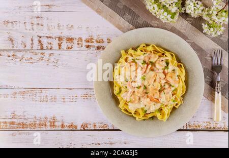 Fettuccine di pasta italiana con salsa alfredo e gamberetti in piatto. Vista dall'alto. Foto Stock