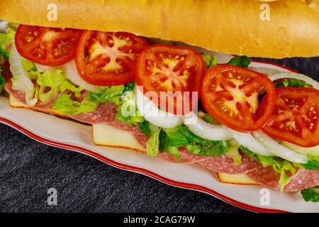 Sandwich con salame, formaggio e verdure su fondo nero. Foto Stock