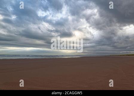 L'ampio tratto di sabbia deserta a St Cyrus Beach a basso Tide sotto i cieli drammatici di una tempesta estiva a settembre. Foto Stock