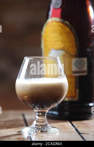 Colpo verticale di un bicchiere di un cocktail russo bianco con vodka, liquore e crema su un tavolo di legno Foto Stock