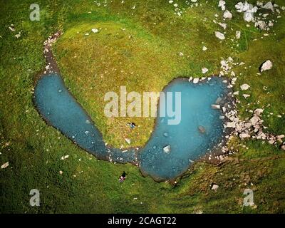 Vista dall'alto dei laghi di montagna blu e di due piccoli turisti. Scatto aereo sul drone Foto Stock