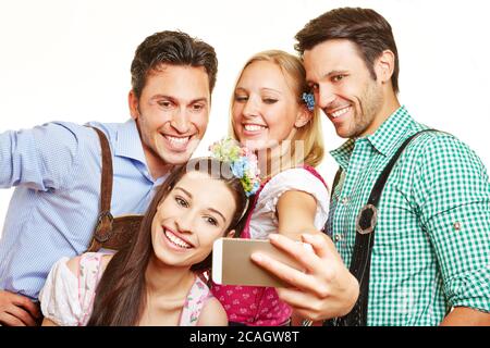 Quattro amici felici in costume bavarese scattano foto con lo smartphone Foto Stock