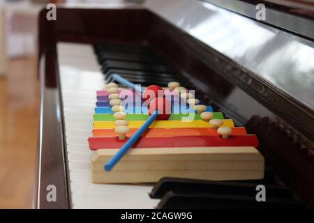 Primo piano immagine di un colorato xilofono giocattolo con malletti messi sulla tastiera di un pianoforte classico. Foto Stock