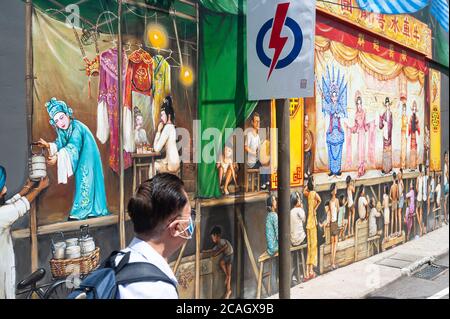 06.07.2020, Singapore, , Singapore - UN uomo con un boccaglio cammina oltre un manifesto elettorale del Partito d'azione popolare (PAP) al potere nel CH Foto Stock