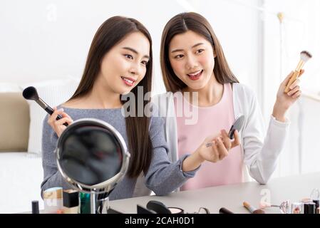 Due belle asiatiche bellezza influencer amici ragazza saluto pubblico mentre registrazione dal vivo a casa Foto Stock