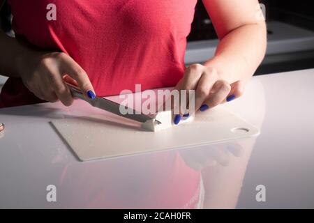 Donna che affetta pane di segale su un tagliere di legno. Un pezzo di  parmigiano, pomodori ciliegini, un piccolo camioncello di formaggio in  primo piano. Moody nat Foto stock - Alamy