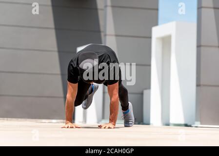 Uomo sportivo in forma facendo scalatori di montagna esercizio all'aperto sulla costruzione pavimento sul tetto in luce solare Foto Stock