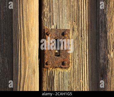 Vecchia serratura con foro per chiave arrugginita su una porta di legno intemperie Foto Stock