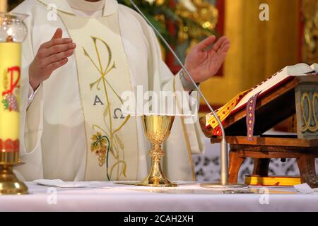 Calice sull'altare e sacerdote che celebra la messa nel sfondo e spazio vuoto per il testo Foto Stock