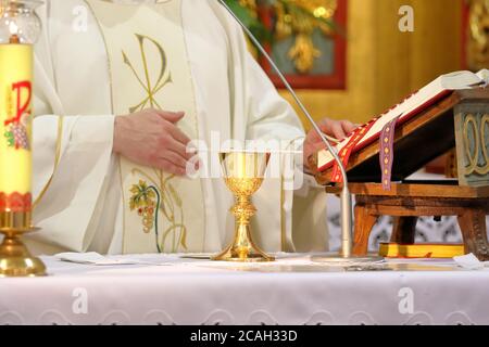 Calice sull'altare e sacerdote che celebra la messa nel sfondo e spazio vuoto per il testo Foto Stock