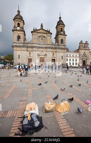 Bogotà, la Candelaria, Colombia - Plaza de Bolivar e Cattedrale nella piazza principale del centro con prodotti di mais di un vend di strada Foto Stock