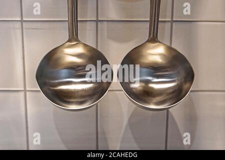 Due mestoli per zuppe in acciaio inox appesi in cucina Foto stock - Alamy