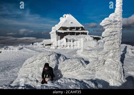 Rifugio, ghiaccio e neve racchiusi, donna con cane, a Szrenica, nella catena montuosa di Karkonosze, monti Sudetes, Parco Nazionale di Karkonosze, Polonia Foto Stock