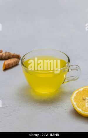 Tazza di tè curativo curcuma con limone e zenzero sfondo neutro di calcestruzzo Foto Stock