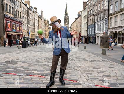 Edimburgo, Scozia, Regno Unito. 7 agosto 2020. In quello che sarebbe stato il giorno di apertura del 2020 cancellato Edinburgh Fringe Festival, Street performer e mago, Dr Love si prepara a intrattenere il pubblico sul Royal Mile nella città vecchia. Indossava i DPI e osservava rigide regole di allontanamento sociale e si esibiva all'interno di un'area defilata per evitare la formazione di folle. Iain Masterton/Alamy Live News Foto Stock