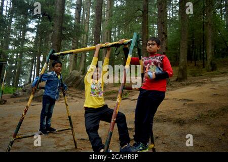 Tre ragazzi adolescenti indiani che si arrampicano su un telaio di un'altalena nel parco di Manali godendo di una messa a fuoco selettiva Foto Stock