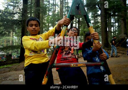 Tre ragazzi adolescenti indiani che si arrampicano su un telaio di un'altalena nel parco di Manali godendo di una messa a fuoco selettiva Foto Stock