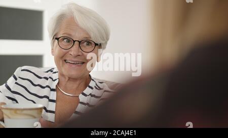 Concetto di pensionamento. Donna anziana che beve il caffè del tè e ridendo. . Foto di alta qualità Foto Stock