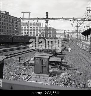 Anni '60, storica, Tokyo, Giappone, numerose linee ferroviarie e treni su binari ferroviari, con cavi elettrici in alto a un bivio fuori città. Foto Stock