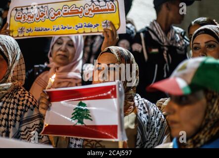Gaza, Palestina. 05 agosto 2020. Una donna palestinese detiene una bandiera libanese e una candela accesa durante una marcia di solidarietà con i libanesi dopo un'enorme esplosione a Beirut Port. Credit: SOPA Images Limited/Alamy Live News Foto Stock