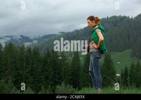 la fotografa di ragazza in montagna spara il paesaggio sul sfondo di una giornata nuvolosa Foto Stock