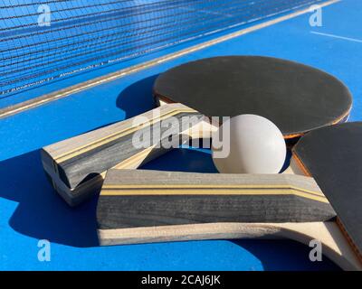 Set di due pipistrelli da ping pong e una palla un tavolo da ping-pong con la rete sullo sfondo Foto Stock