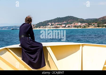 Il vecchio monaco guarda le montagne Athos su una nave in una giornata estiva Foto Stock